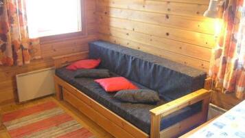 L’intérieur chaleureux d’un chalet avec un canapé-banquette en bois, un radiateur et un tapis à rayures.