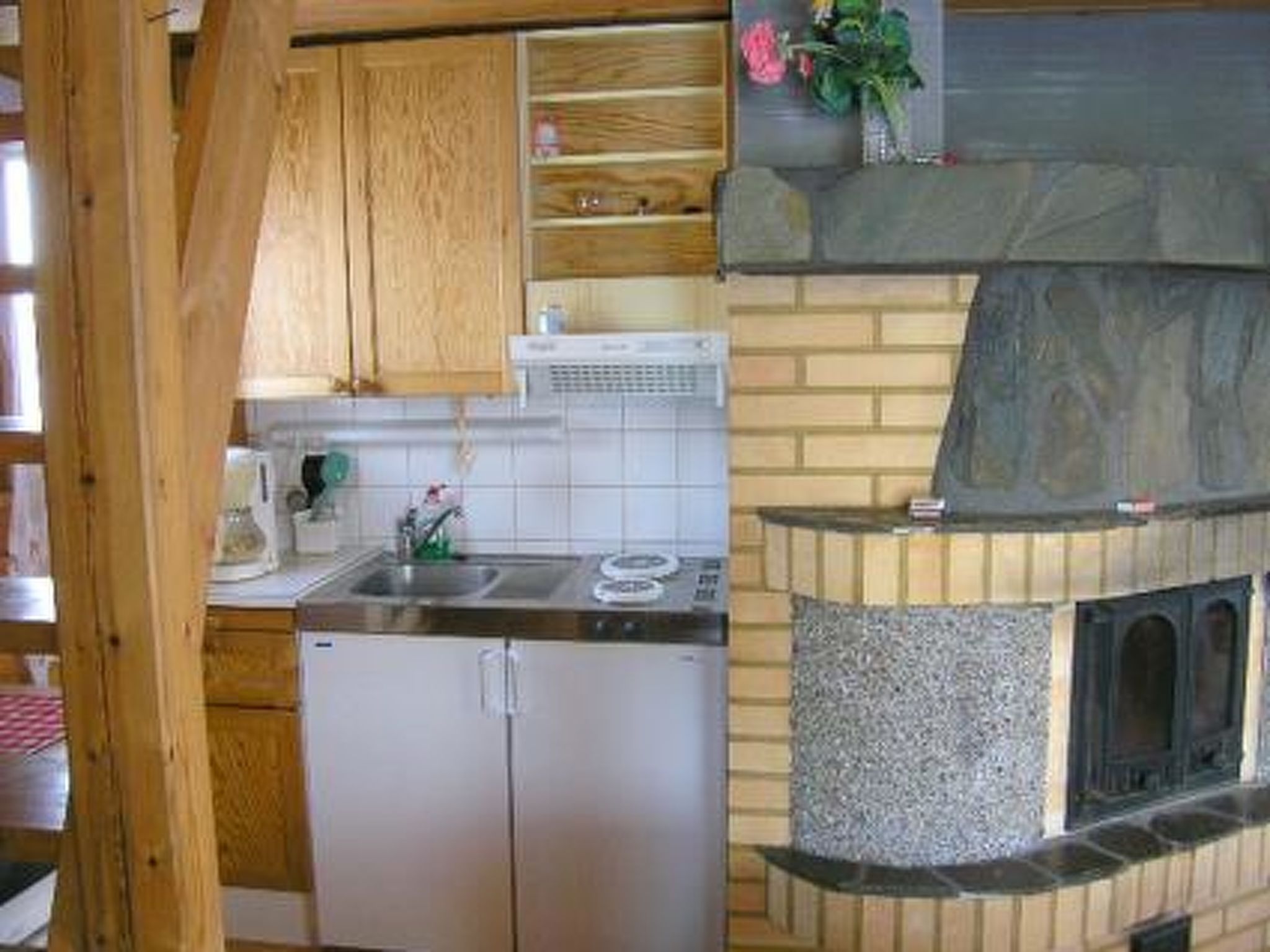Une cuisine dotée d’une cheminée en pierre, de meubles en bois et d’un réfrigérateur en acier inoxydable.