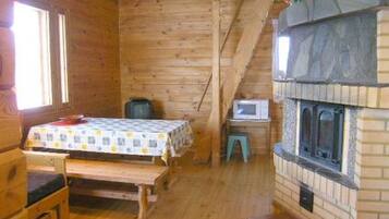 A cozy wooden cabin room with a bed, a small table, a television, and a fireplace.