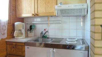 A compact kitchen with wooden cabinets, a built-in microwave, a coffee maker, and a small sink.