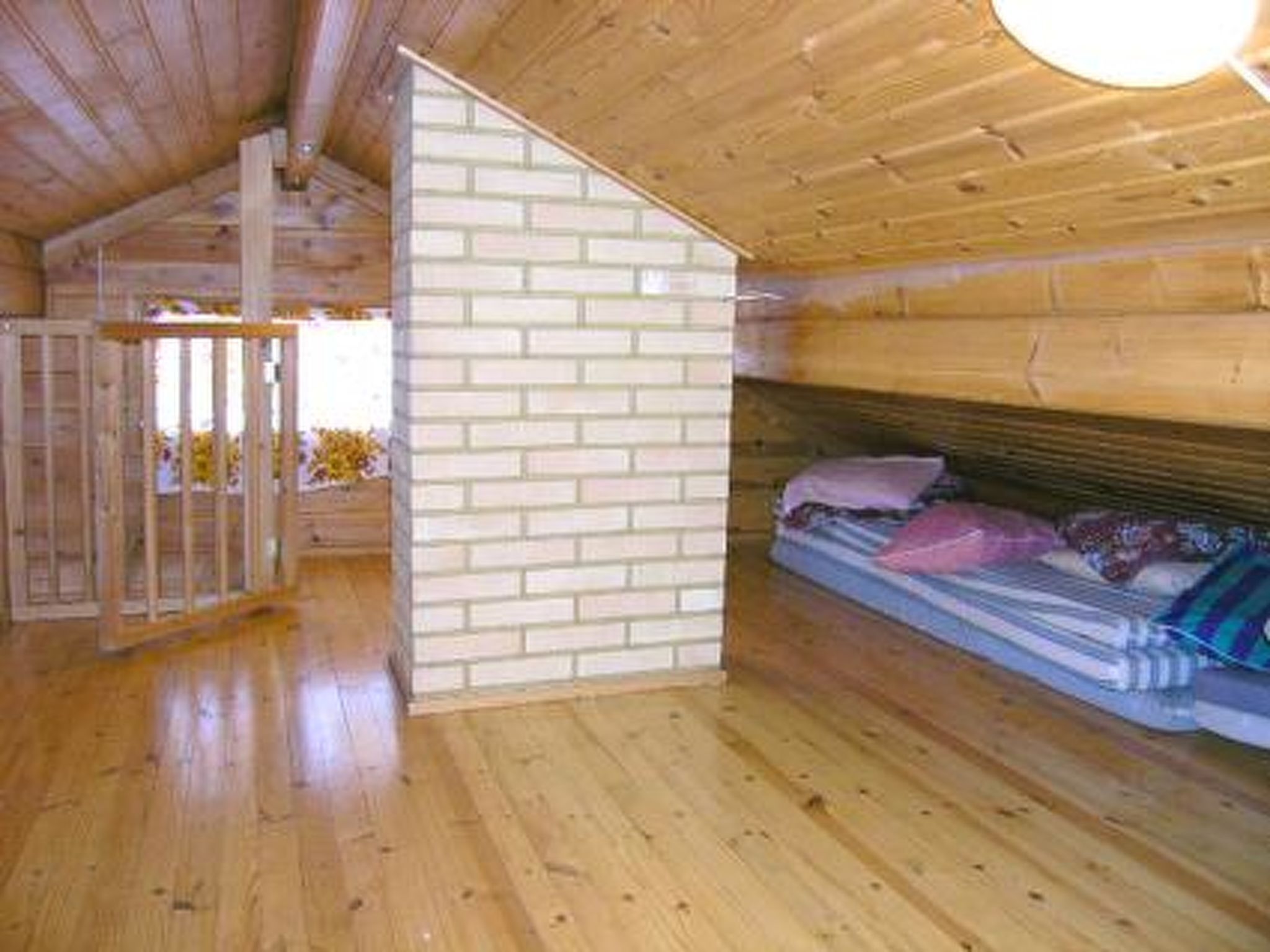 Een houten chalet van binnen, met een stapelbed, een houten vloer en een bakstenen muur.