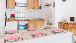 Eine kleine Küche mit Holdekor-Schränken, einer weißen Fliesenspiegel und einem Essbereich, der für eine Mahlzeit gedeckt ist.