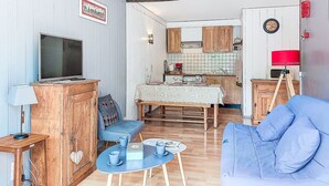 Ein kompakter Wohnbereich mit Fernseher, Holzmöbeln, Esstisch und Küchenzeile.