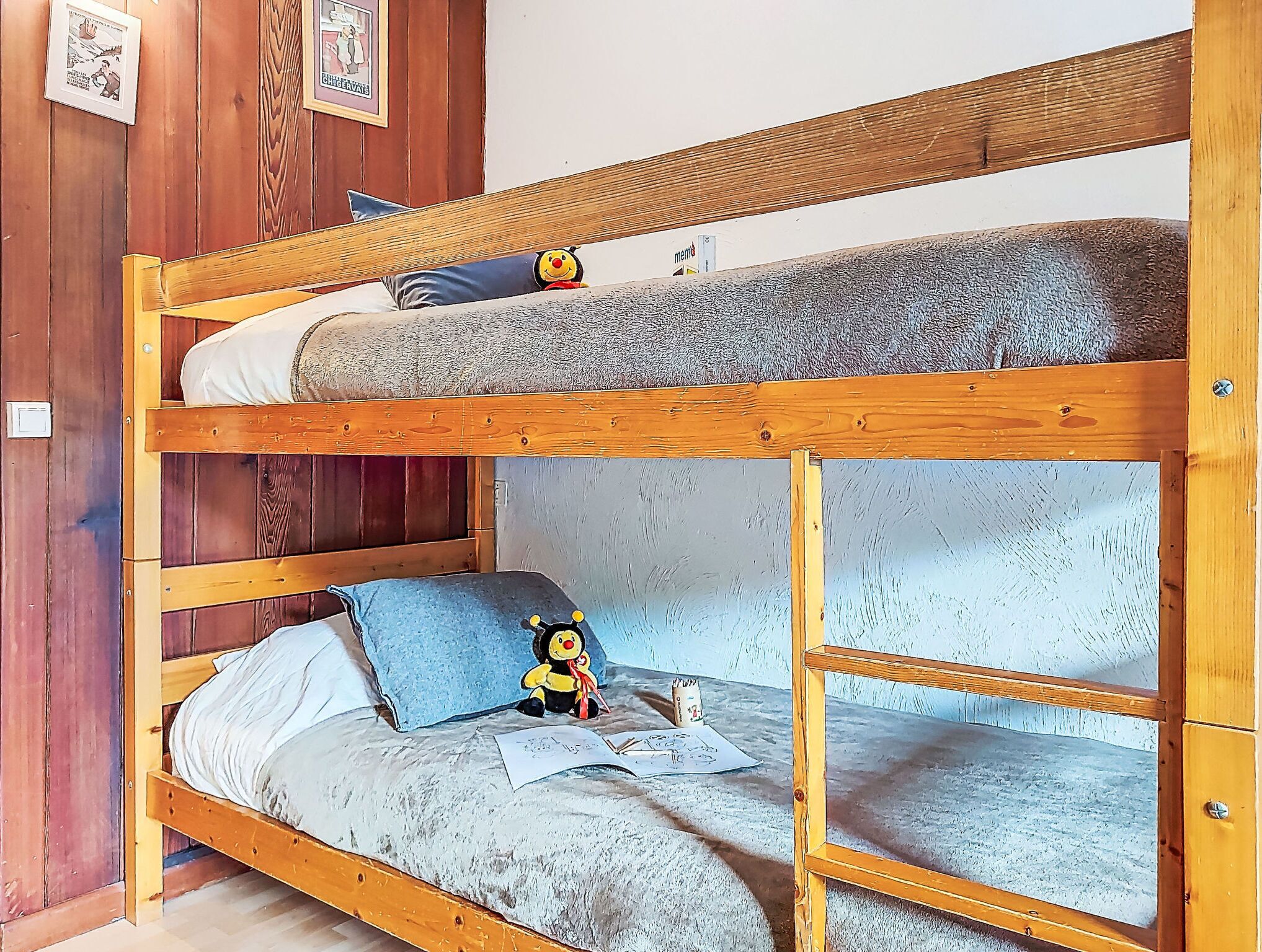 Un letto a castello con un cuscino blu e un peluche nel letto inferiore.