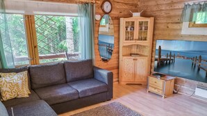 A cozy living room with a grey sofa, a wooden cabinet, and a TV displaying a scenic view.