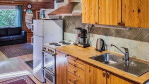A compact kitchen with wooden cabinets, a stove, a sink, and a coffee maker.