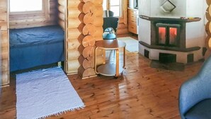 Een gezellig cabin interieur met een houten wand, een open haard, een blauwe bank en een kleine ronde tafel.
