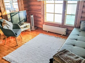 Een gezellige woonkamer met een televisie, een ventilator, een radiator en een bank.