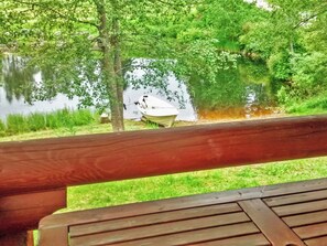 A wooden deck overlooking a calm lake with a boat docked on the shore. - Sillankorva by Interhome (Lapinlahti)