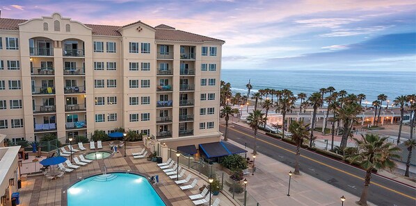 A hotel with a pool, lounge chairs, and a view of the ocean.