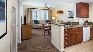 Ein Hotelzimmer mit einer Küchenzeile, einem Sofa, einem Esstisch und Blick auf die Stadt.