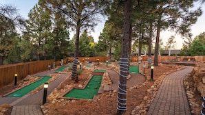 A miniature golf course with multiple lanes, wooden fences, and trees.