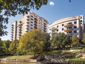 Un edificio residenziale a più piani con balconi, immerso nel verde e con una piccola fontana.