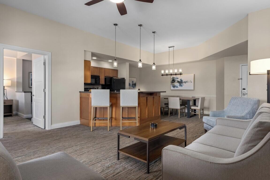 A modern living room with a sofa, coffee table, and a dining area with a table and chairs.