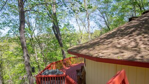 A wooden deck with a red railing, a small shed, and a tree in the background.
