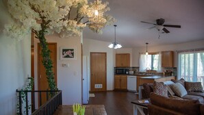 A spacious living area with a wooden dining table, a brown leather sofa, and a kitchen in the background.