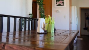 A wooden dining table with a vase of white flowers and a hanging light fixture.