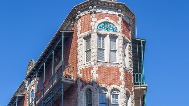 A corner building with a stone facade, multiple windows, and a balcony.