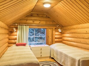 A log cabin room with two beds, a window, and a small table. - Tuulikannel by Interhome (Asikkala)