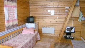 A small, wooden cabin room with a single bed, a television, a small table, and a microwave.