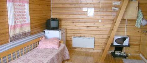 Une petite pièce de cabane en bois comprenant un lit simple, un téléviseur, une petite table et un four à micro-ondes.