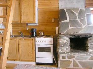 A kitchen with wooden cabinets, a stove, and a stone fireplace.