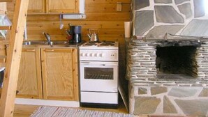 A kitchen with wooden cabinets, a stove, and a stone fireplace.