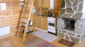 A kitchen with wooden cabinets, a stove, and a stone fireplace.