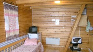 A small, wooden cabin room with a single bed, a television, a small table, and a microwave.