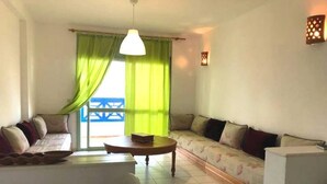 A living room with a sofa, a coffee table, and a small table with a book. - Residence Cite Jardin 4080 (Martil)