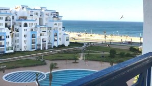 A hotel with multiple white buildings, a pool area, and a view of the beach and ocean. - Residence Cite Jardin 4080 (Martil)