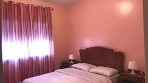 A bedroom with a single bed, two bedside tables, and a window with curtains. - Residence Cite Jardin 4080 (Martil)