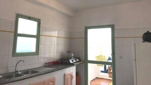 A kitchen with white tiles, a sink, a stove, and a refrigerator. - Residence Cite Jardin 4080 (Martil)