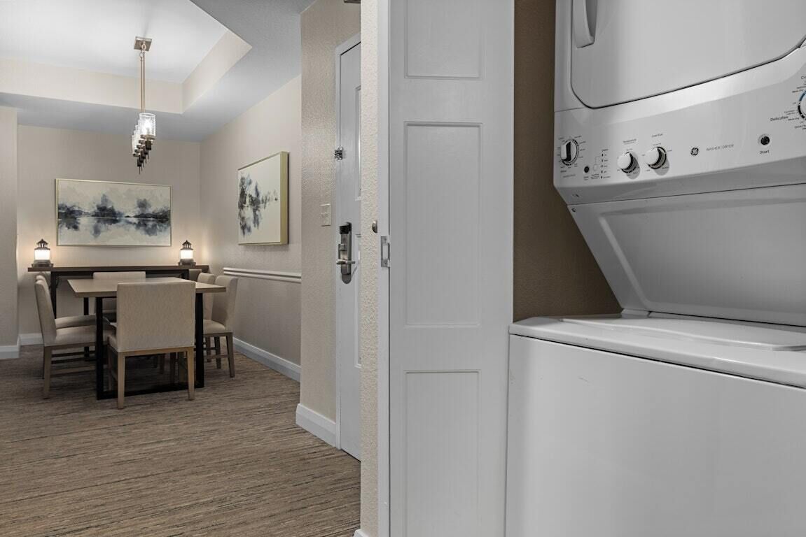 A modern room with a dining area, a washing machine, and a door.