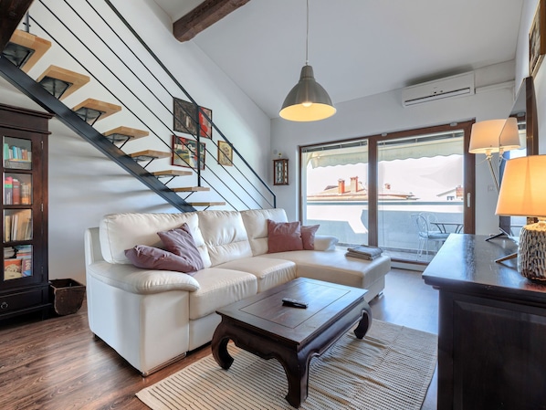 A modern living room with a white leather sofa, a wooden coffee table, and a staircase with skylights. - Apartment Olivo by Interhome (Novigrad (Istra))