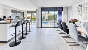 Una cocina moderna con una isla central, taburetes de bar y un comedor con sillas y una mesa.