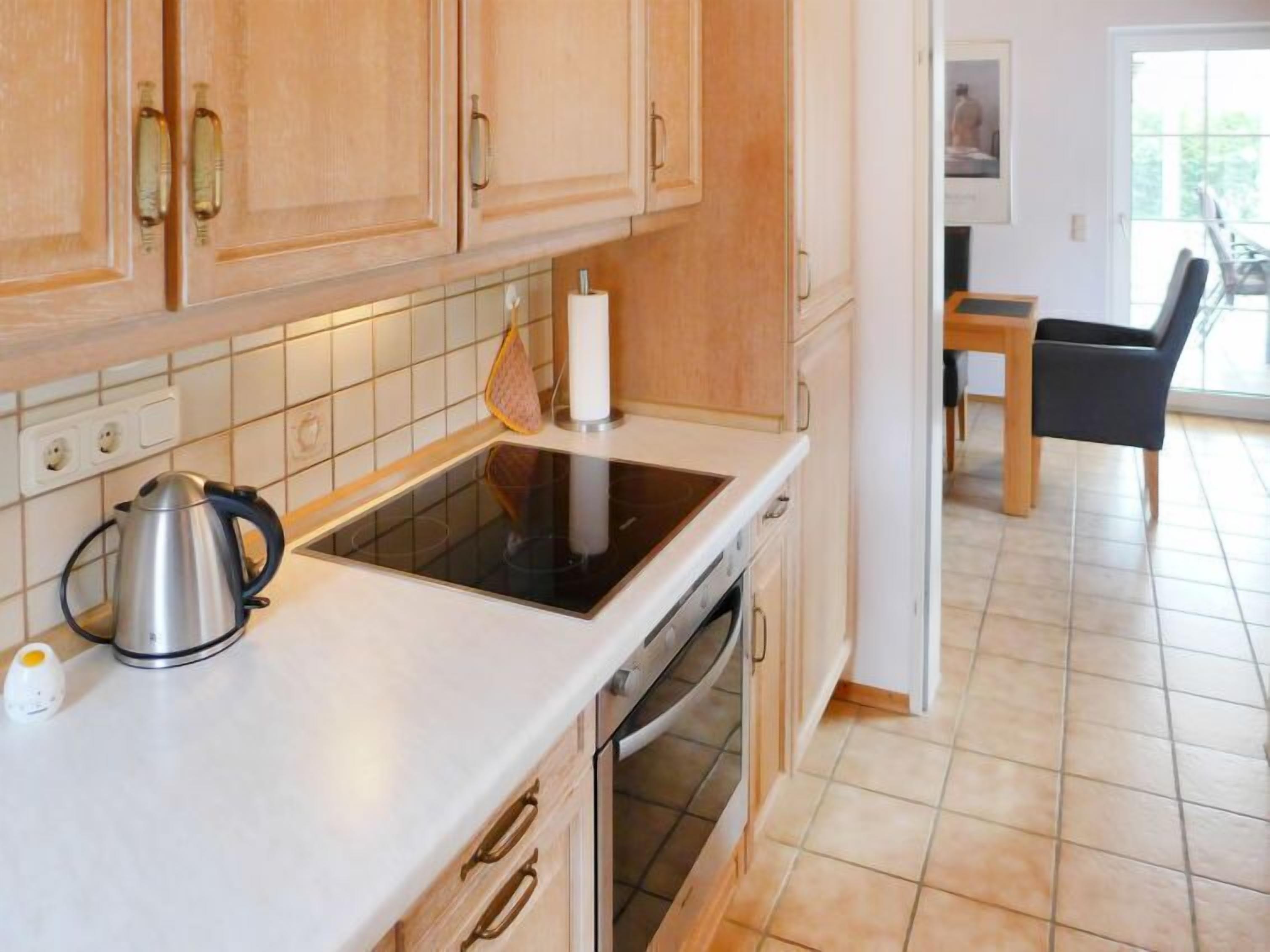 A kitchen with wooden cabinets, a stove, and a kettle.