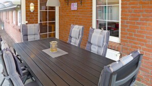 A rectangular wooden table with a glass pitcher, surrounded by six upholstered chairs with striped cushions. - Vacation home Reuse by Interhome (Norddeich)