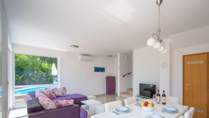 Een moderne woonkamer met een bank, eettafel en televisie.