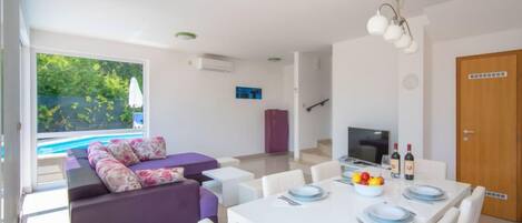 Moderni olohuone, jossa on sohva, ruokapöytä ja televisio.