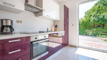 Een koelkast, een oven, een vaatwasser, kookgerei, borden en bestek