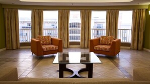 A room with two orange armchairs, a glass-top table, and large windows with curtains. - Relax at our Palm Tree secluded Resort with a poolside bar and waterslide (Pompano Beach)