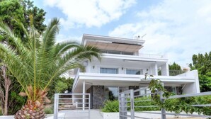 Een modern herenhuis met twee verdiepingen, een hekpoort, een gevel van natuursteen en een balkon.
