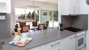Een moderne keuken met een groot eiland, roestvrijstalen apparatuur en een eetgedeelte met uitzicht.