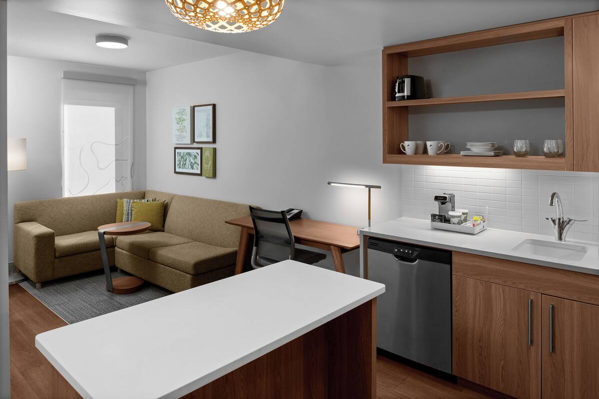 A modern kitchen with a dining area, wooden cabinets, and a built-in dishwasher.