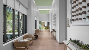 A modern hotel corridor with large windows, a green ceiling, and a wall with decorative planters. - Element by Marriott Scottsdale at SkySong (Scottsdale)