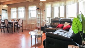 Una sala de estar acogedora con un sofá de cuero, una mesa de comedor, sillas y una mesa de centro de vidrio.
