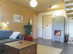Een gezellige woonkamer met een bank, een salontafel, een open haard en een trap.