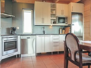 Une cuisine avec des meubles blancs, un four à micro-ondes, une machine à café et un lave-vaisselle.