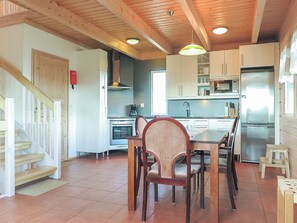 Une cuisine moderne avec des poutres en bois, une table à manger avec des chaises, un réfrigérateur et un four à micro-ondes.